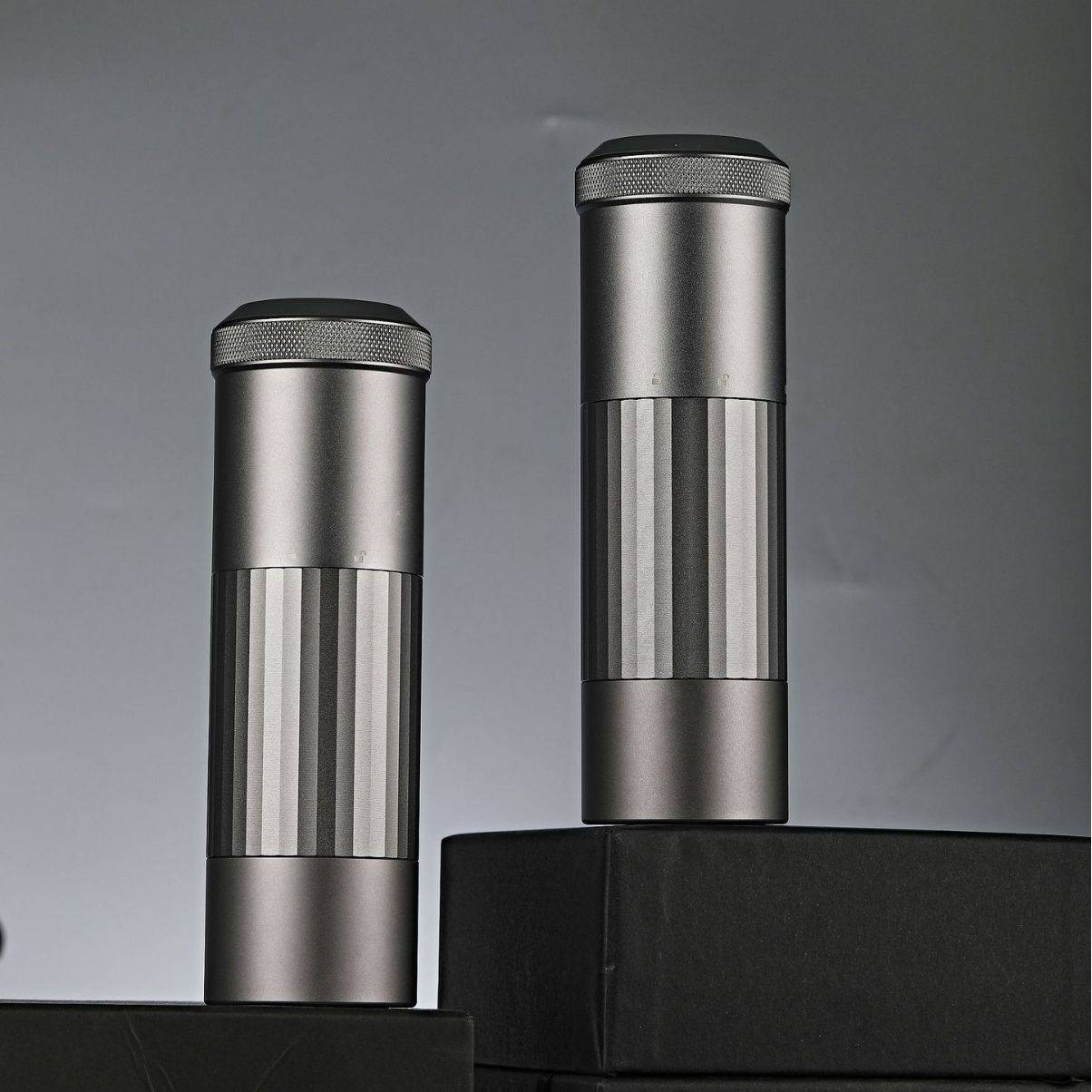 Two Portable Wireless Bean Grinders displayed on black platforms. Minimalist design with USB charging for efficient coffee grinding.