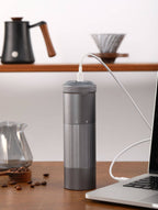 Portable Wireless Bean Grinder connected to a laptop via USB charging. Compact and efficient for fresh coffee grinding anywhere.