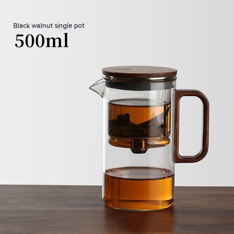 One-Click Filtering Glass Teapot with a walnut wood handle and glass liner. Features a keyless magnetic spin filter for effortless tea brewing.