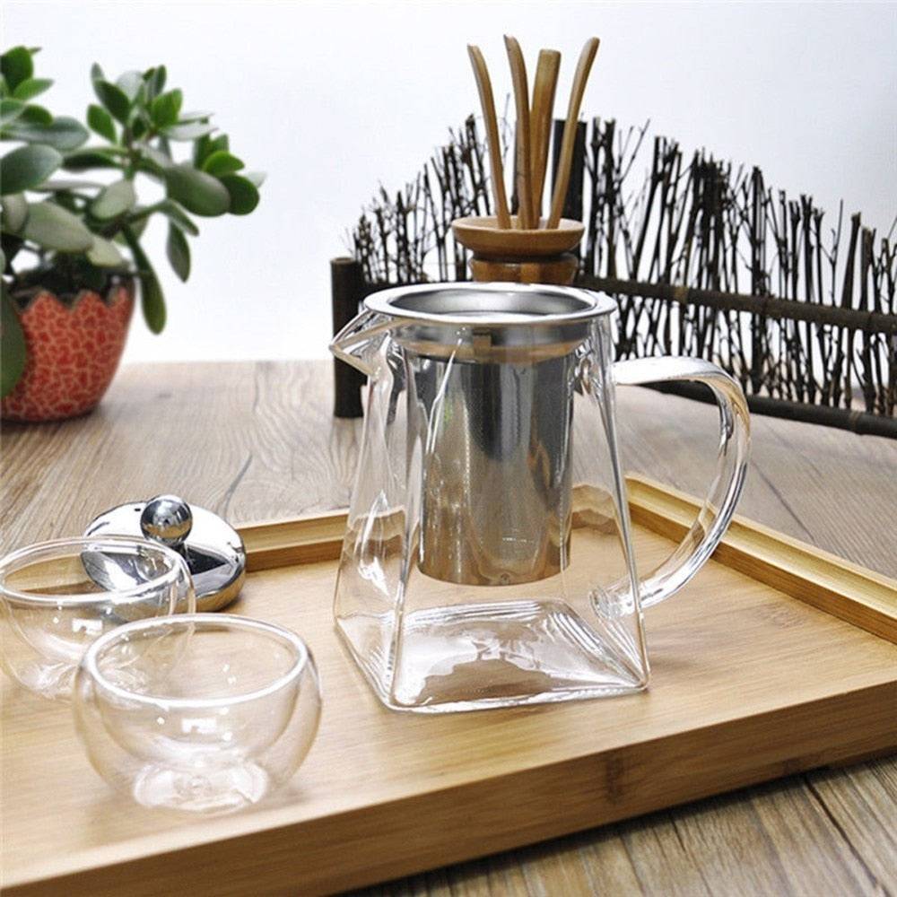 Glass infuser teapot with stainless steel lid and filter, pouring freshly brewed tea into a matching glass cup. Ideal for effortless tea brewing.