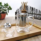 Glass infuser teapot with stainless steel lid and filter, pouring freshly brewed tea into a matching glass cup. Ideal for effortless tea brewing.