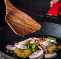 Teak spoon and spatula in a bowl of salad